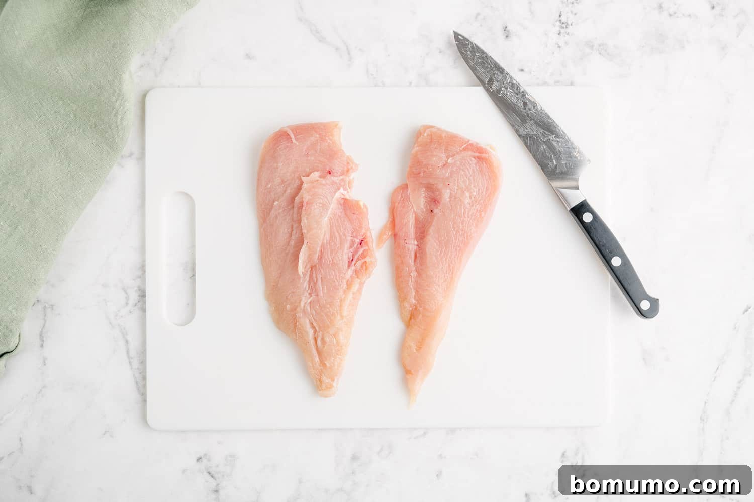 A chicken breast, expertly cut in half to create two thin, even cutlets for cooking.