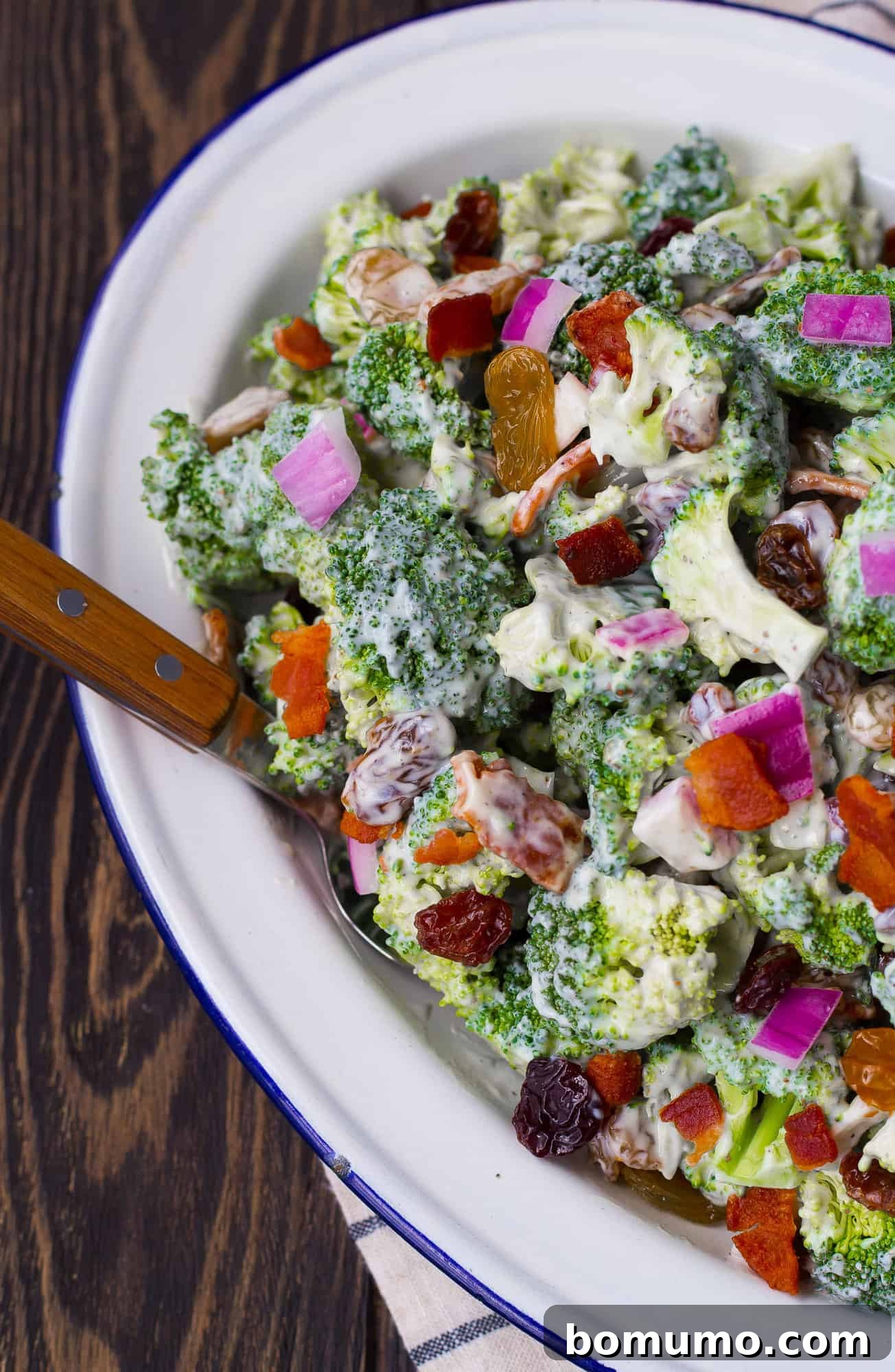 Broccoli salad with bacon, raisin, onion, and a creamy dressing.