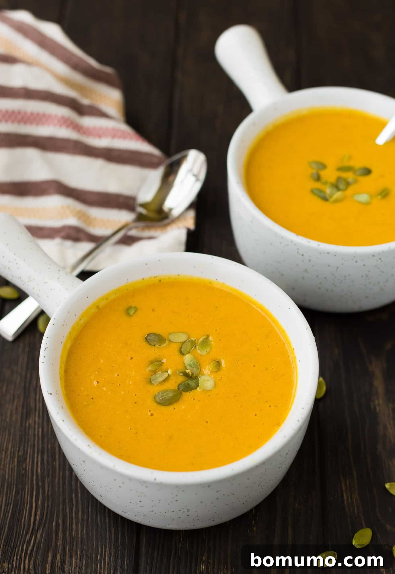Two bowls of pumpkin curry soup with pepitas.