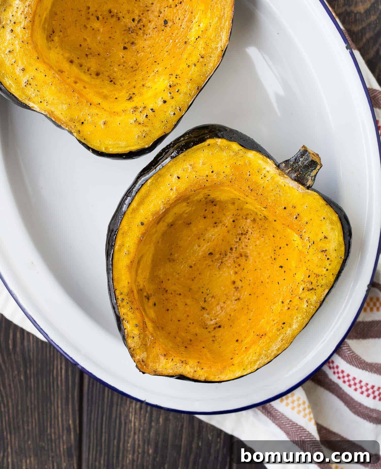 Overhead view of acorn squash half, roasted with pepper.