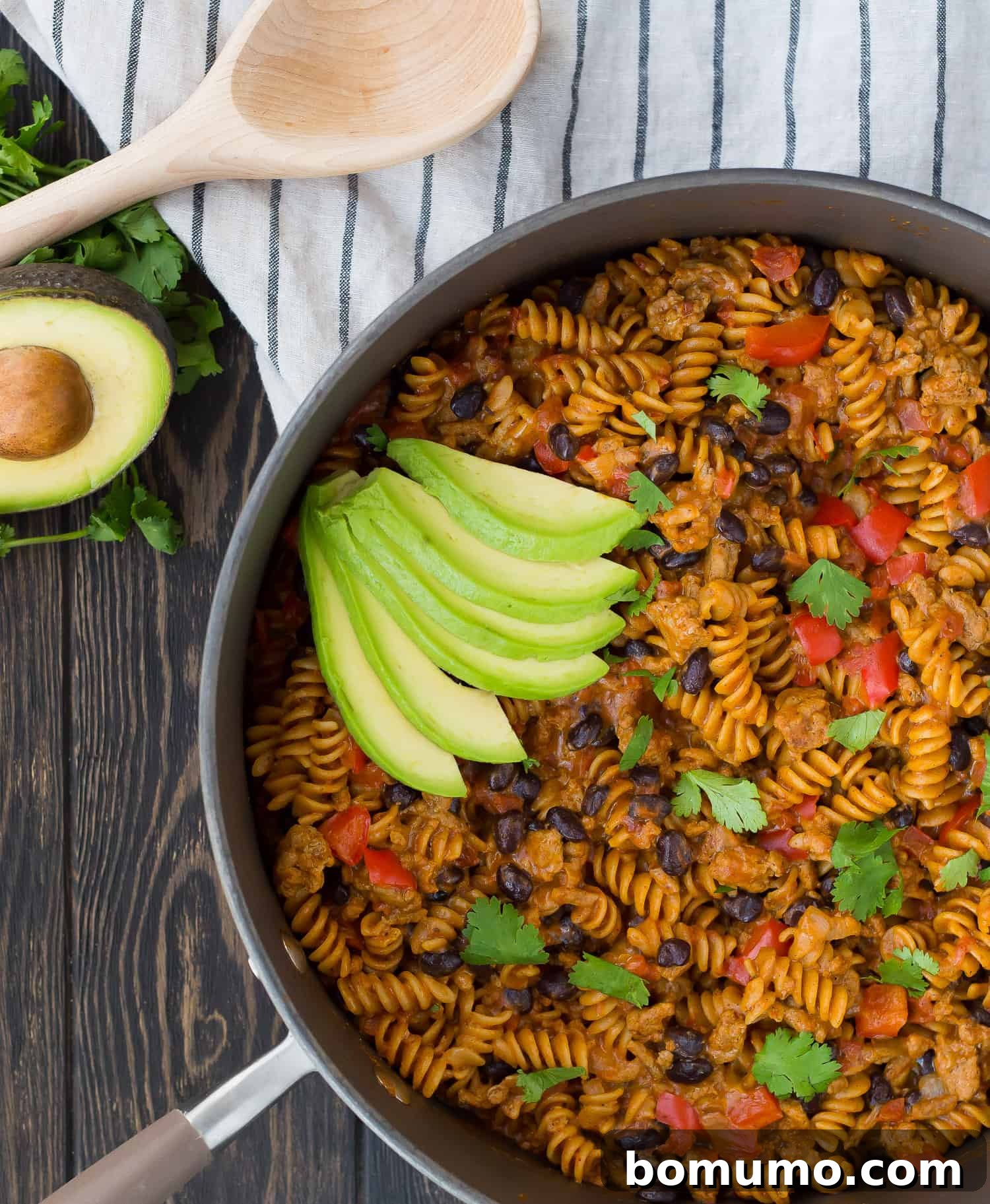 A vibrant One Pan Taco Pasta, rich with ground turkey, black beans, and melted cheese, served directly from a rustic skillet, ready for a quick and easy family dinner.
