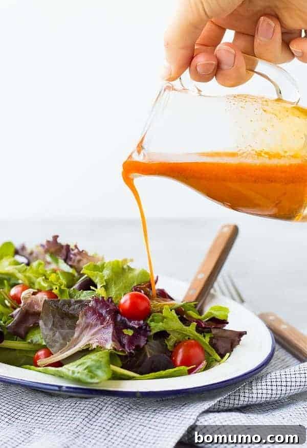 A vibrant orange Carrot Vinaigrette Salad Dressing in a clear jar, ready to be poured over fresh greens, showcasing its natural sweetness and rich flavor profile.