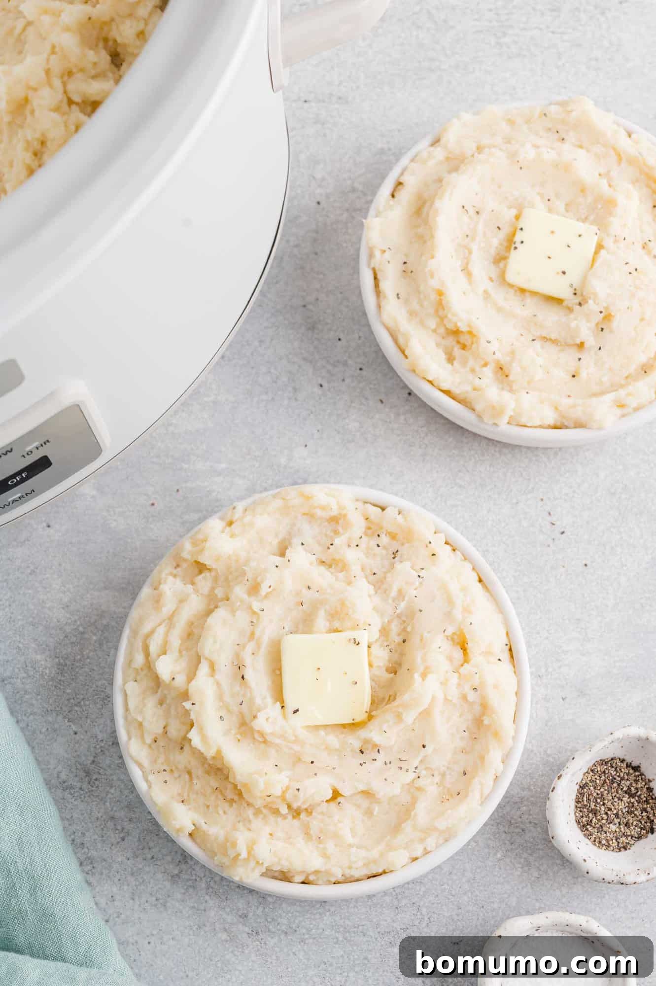 Set-It-and-Forget-It Mashed Potatoes 3 Fluffy mashed potatoes served in two white bowls, with a slow cooker in the background, ready for serving.