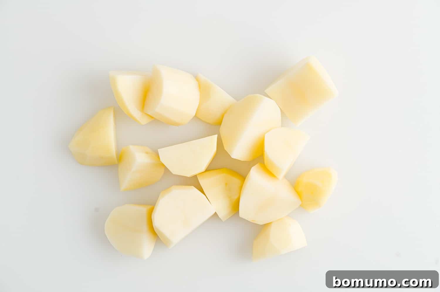 Set-It-and-Forget-It Mashed Potatoes 6 A bowl filled with peeled and uniformly cut potato chunks, ready for slow cooking.