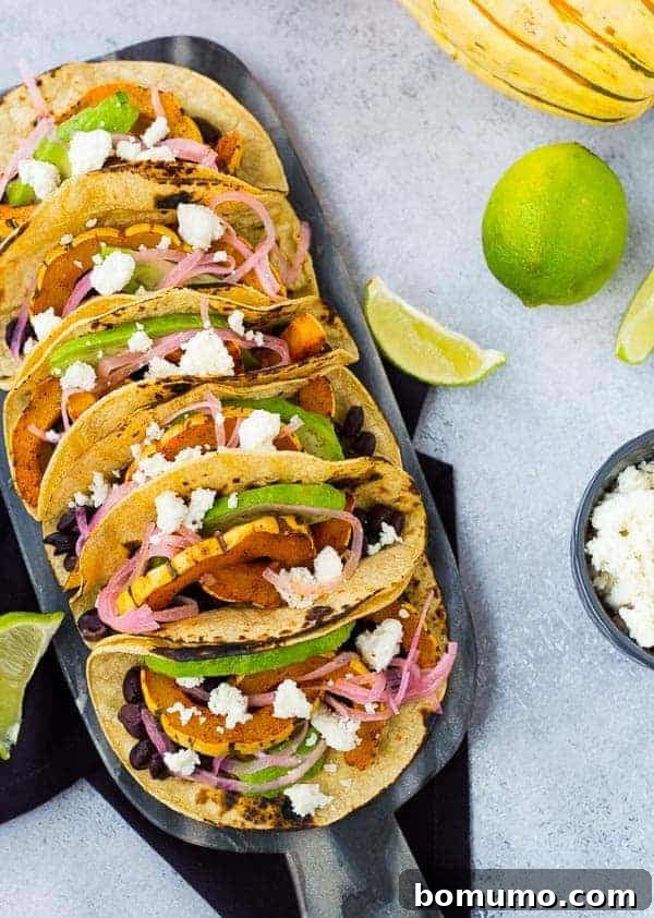 Overhead of several prepared tacos on decorative cutting board.