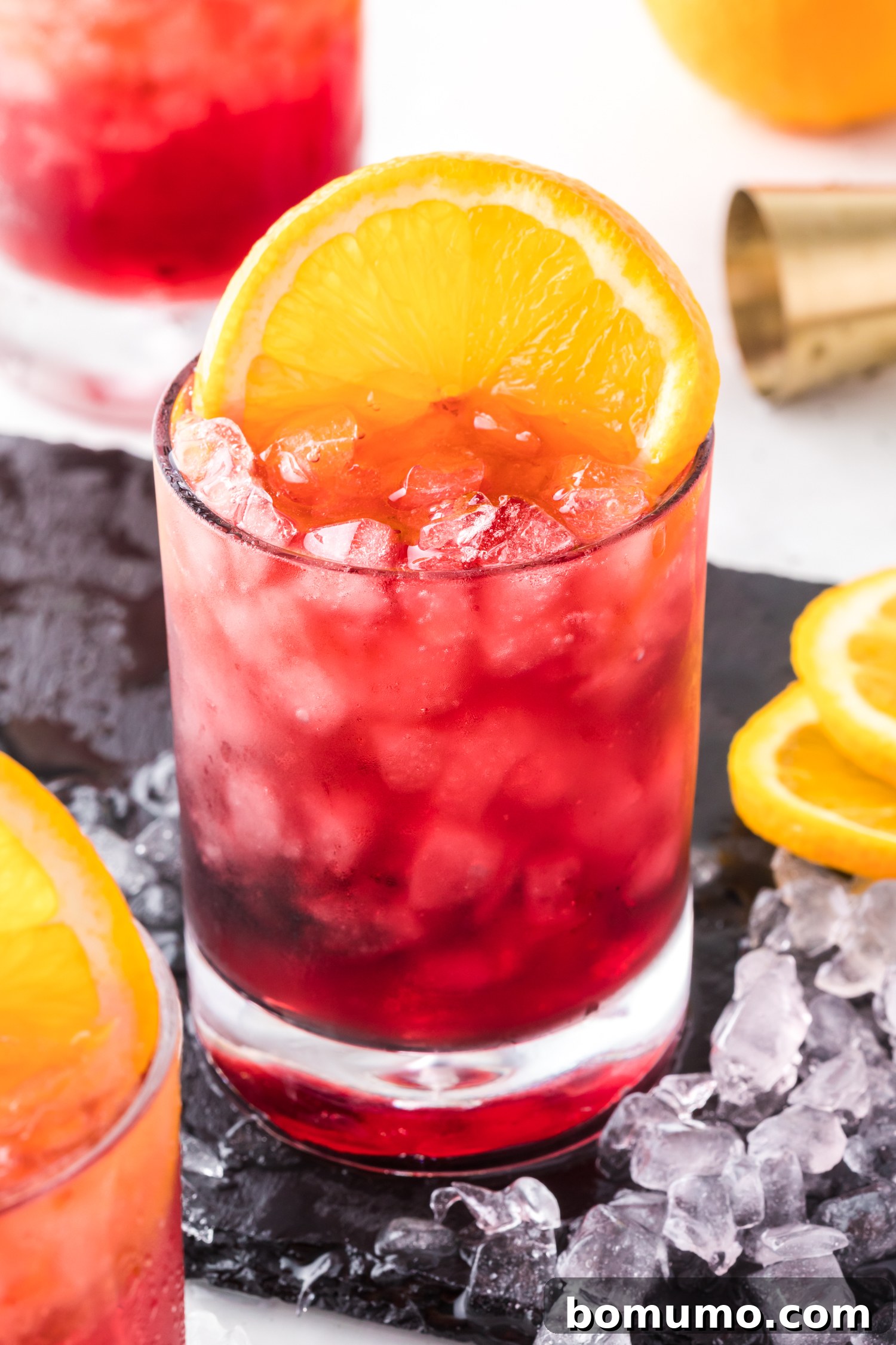 A stunning red wine spritzer, featuring pellet ice and an orange slice, radiating cool and refreshing vibes.