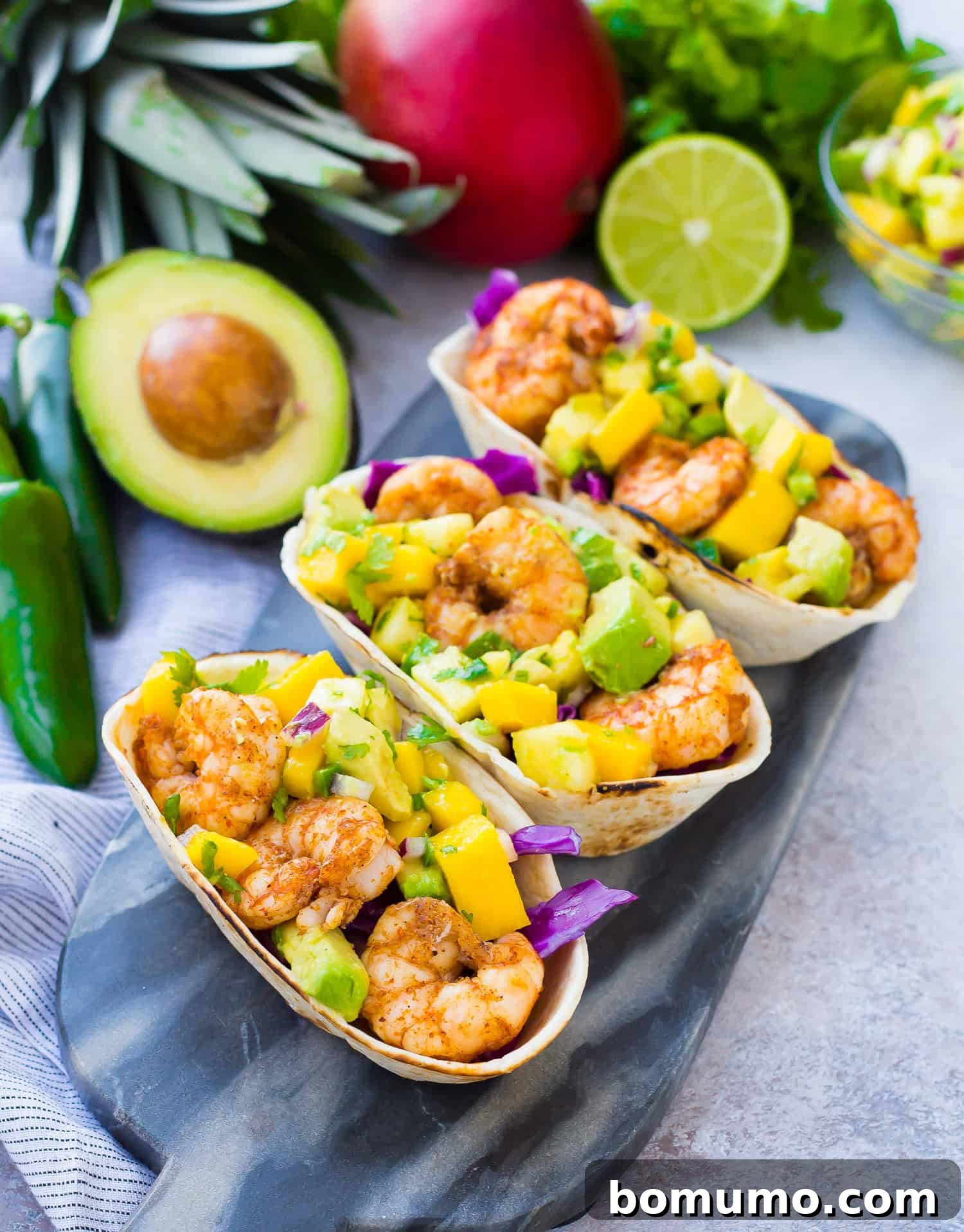 Shrimp tacos with avocado mango salsa, garnished with fresh cilantro and a squeeze of lime.