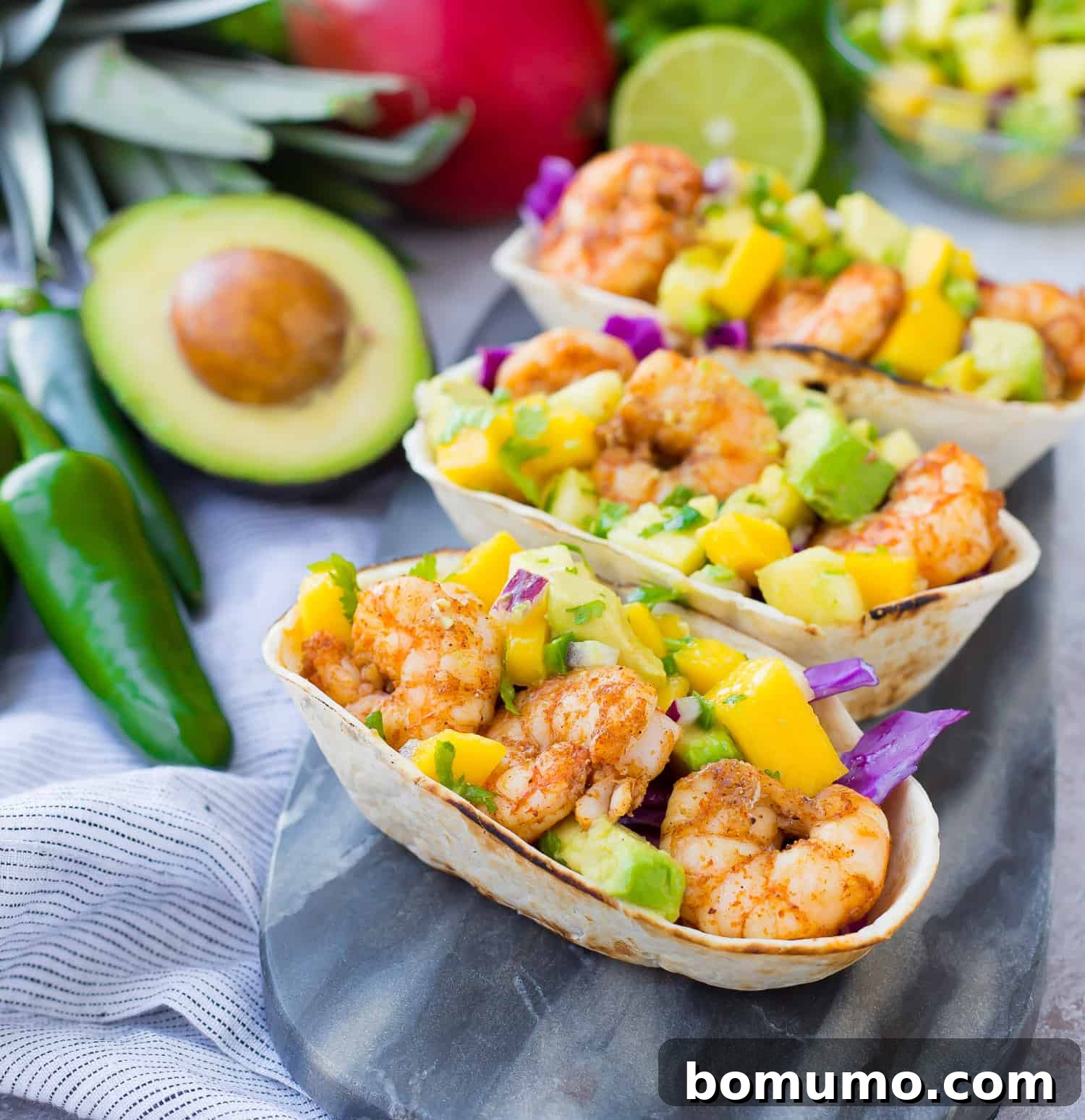 Shrimp tacos artfully arranged in tortilla boats, generously topped with a colorful mango and avocado salsa.
