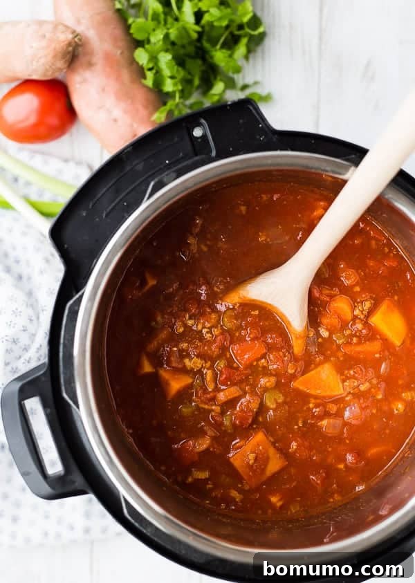 Overhead shot of chili simmering beautifully in an Instant Pot, with a wooden spoon resting in the pot, ready to be stirred and served.