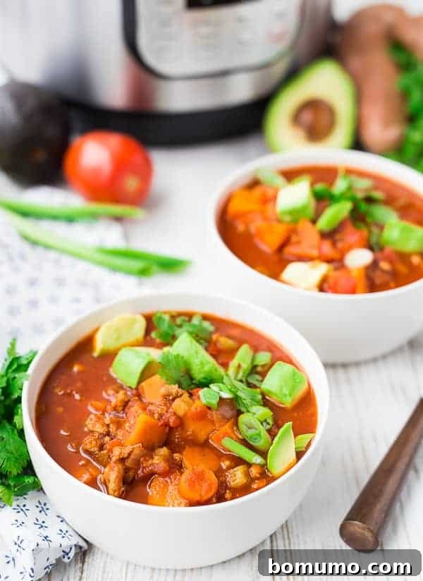 Two generous servings of Instant Pot chili in pristine round white bowls, accompanied by spoons, ready to be enjoyed as a hearty and satisfying meal.