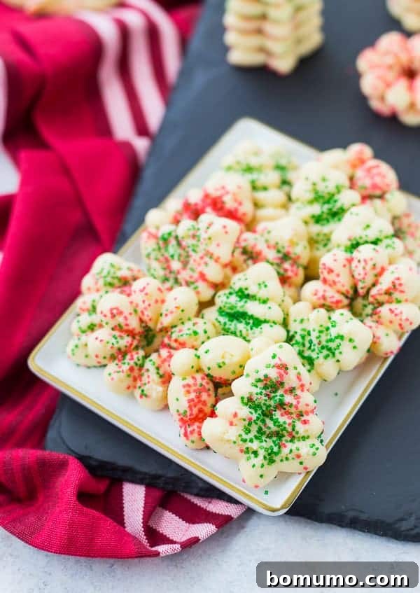 Small plate with several spritz cookies decorated with red and green sugar, perfect for a festive occasion.