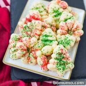 Front view of several spritz cookies on a rectangular white plate, ready to be enjoyed.