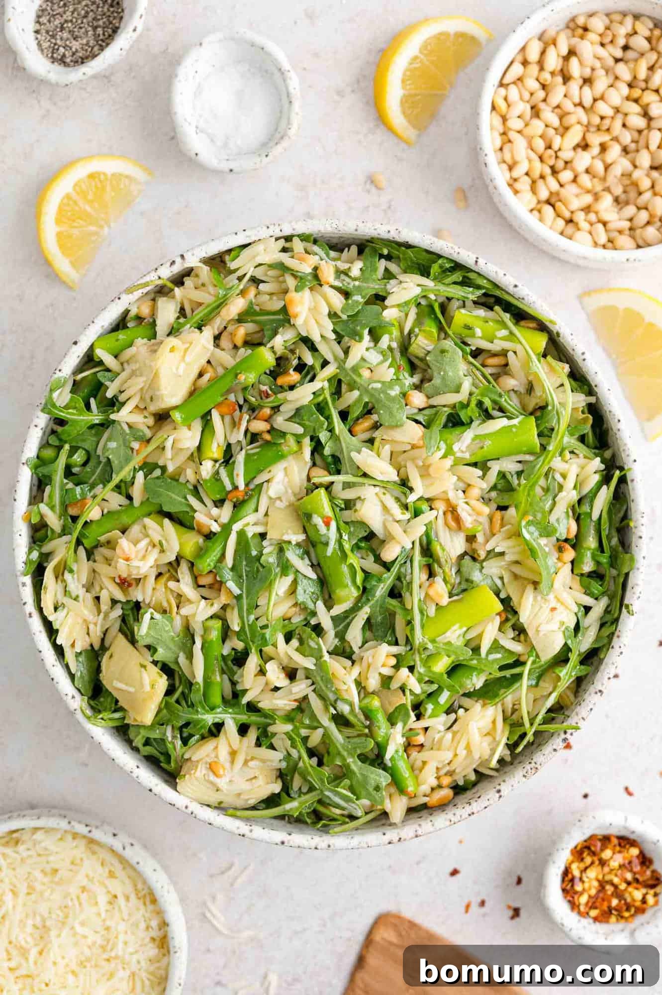 Spring orzo salad with individual ingredients surrounding bowl.