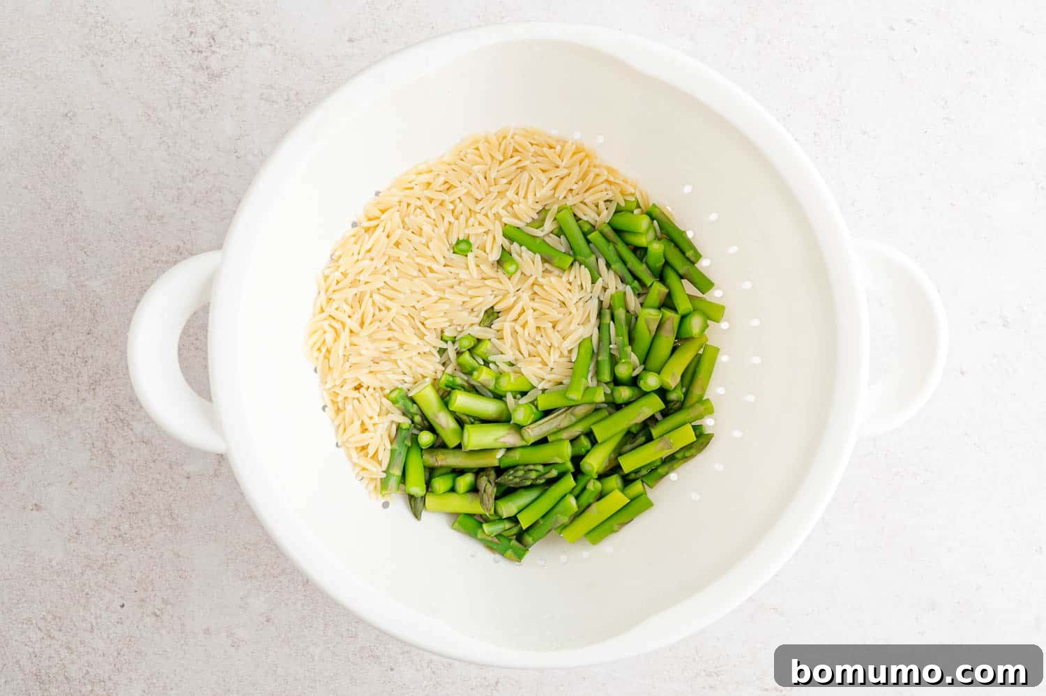 Orzo and asparagus in colander. 