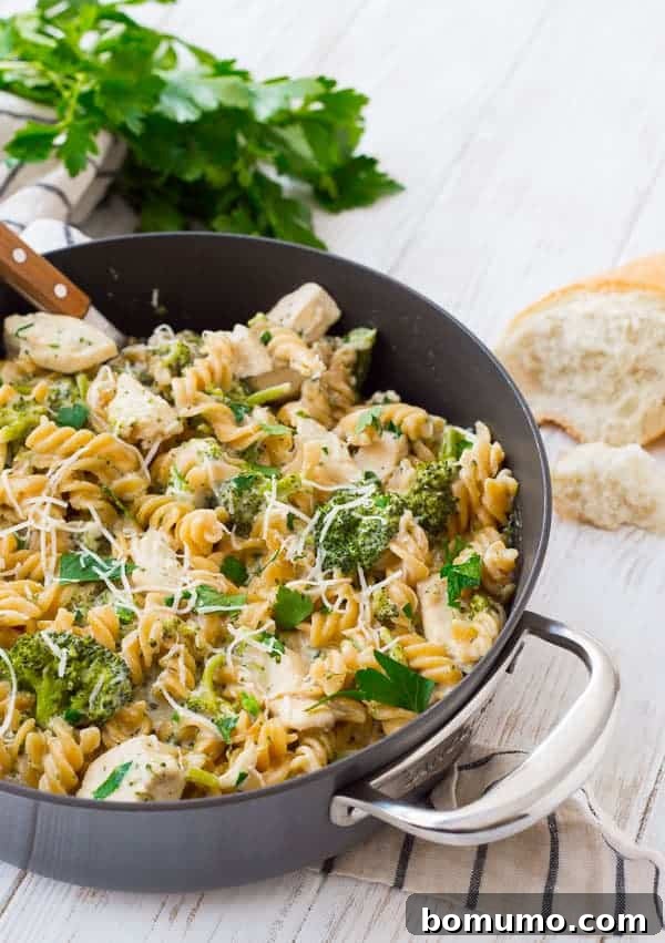 Garnished chicken alfredo with shredded Parmesan and chopped parsley in a skillet