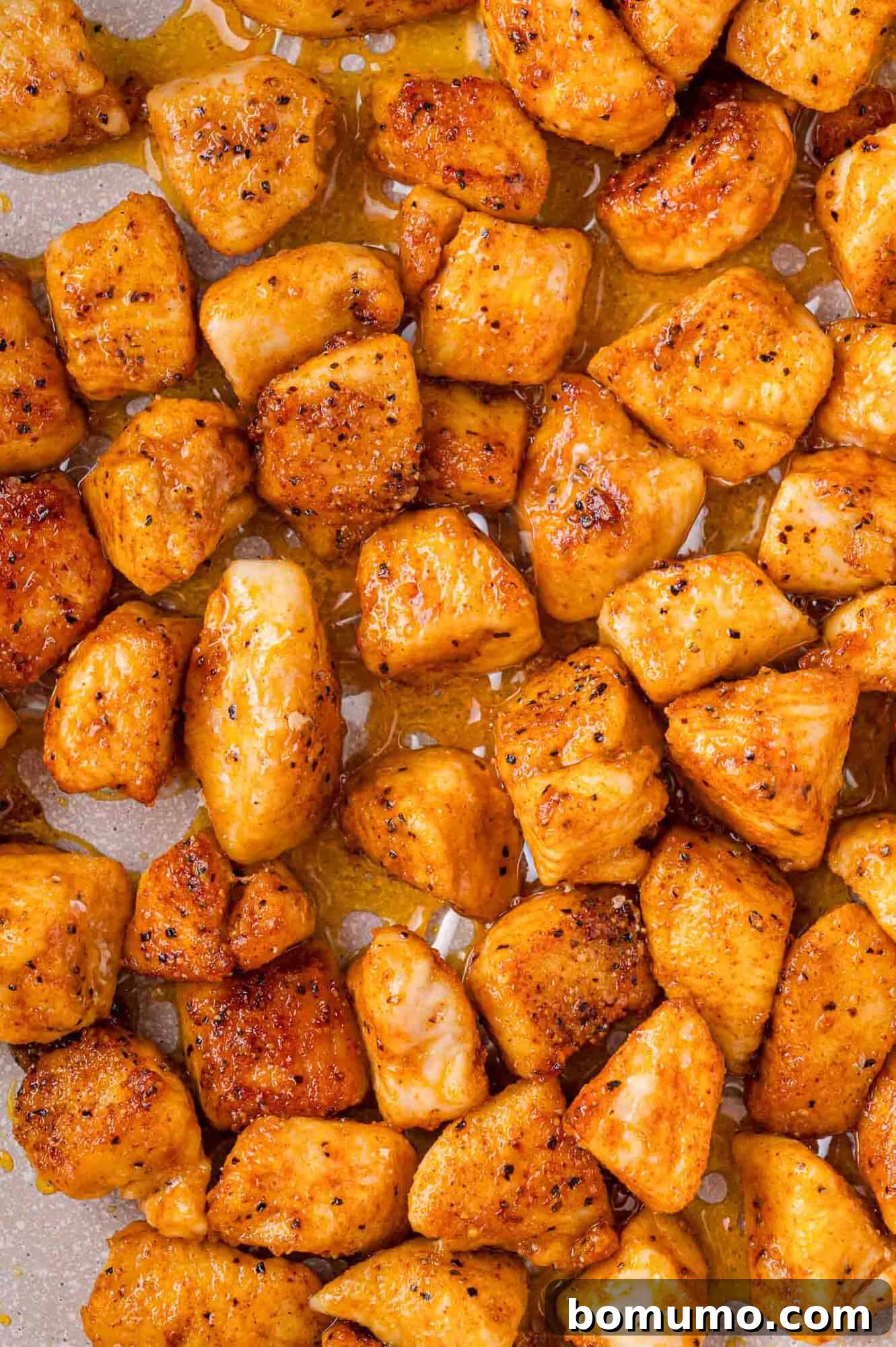 Close-up of seasoned chicken cubes, golden brown and glistening with oil.