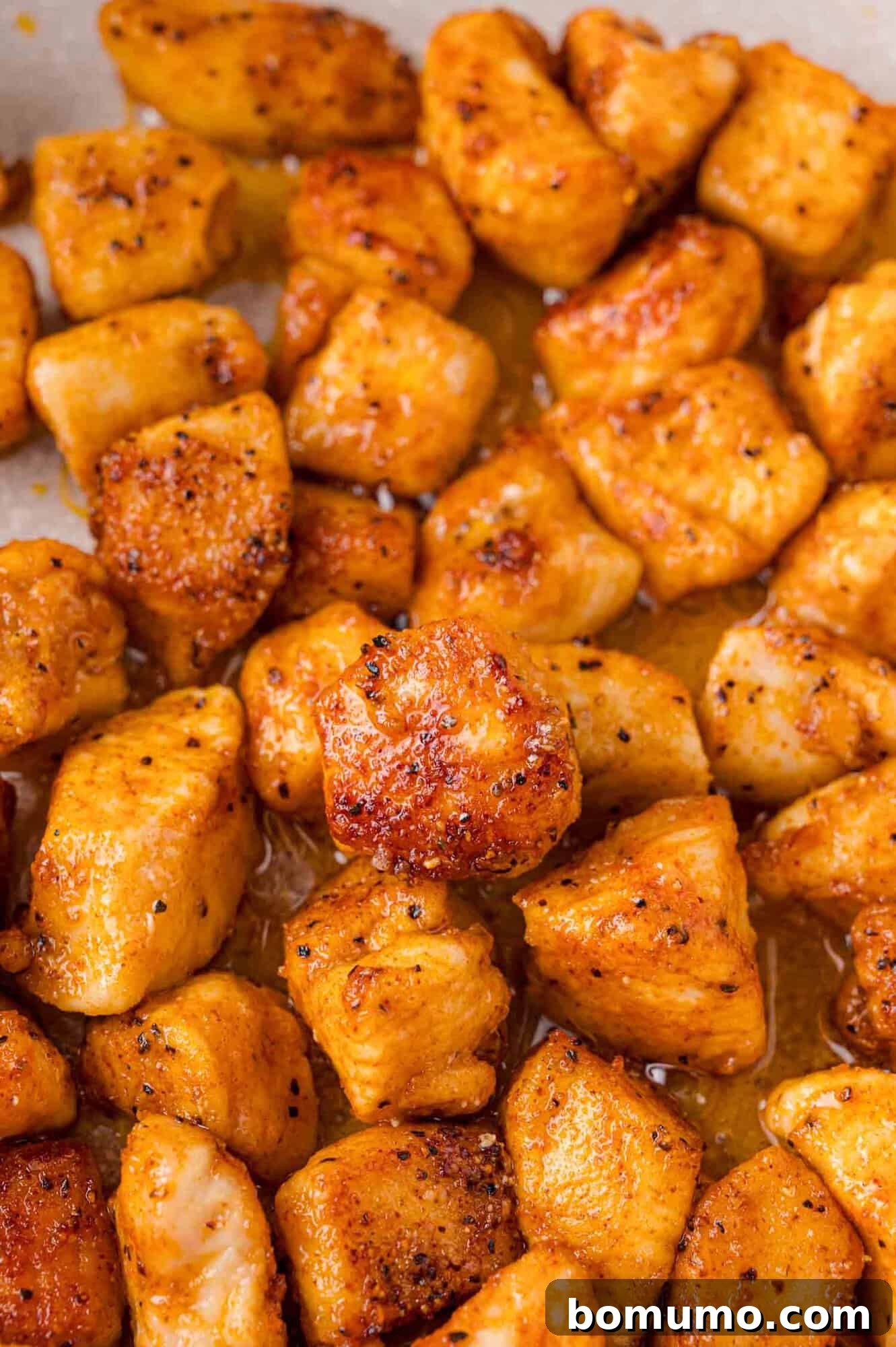 Close-up of cooked, seasoned chicken pieces with a golden-brown color.