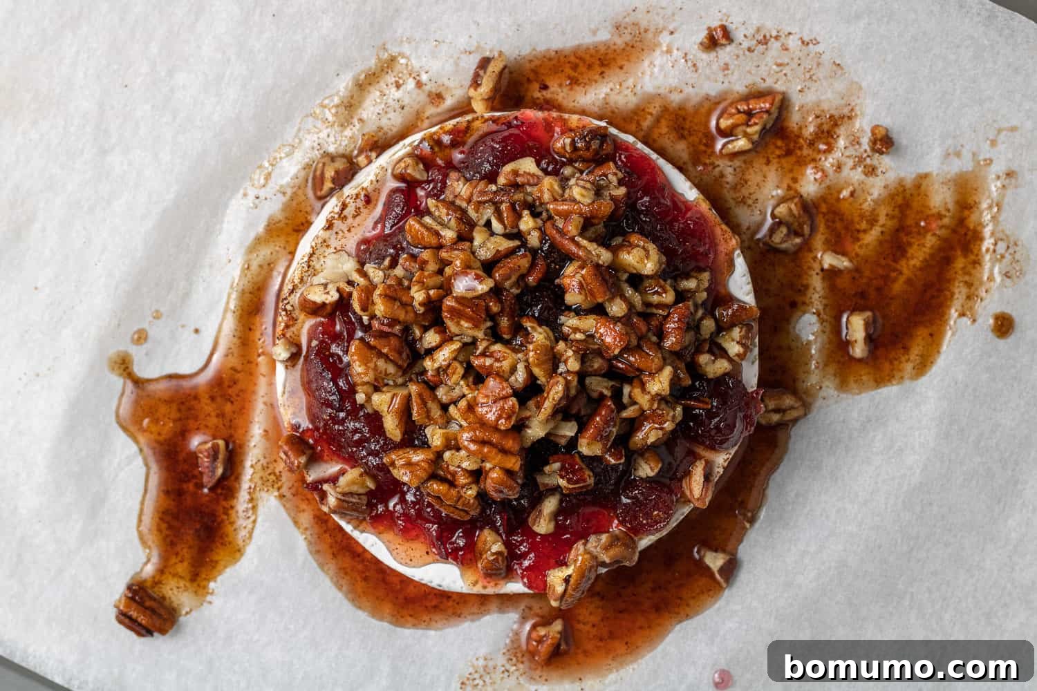 Pecans and cranberries on top of brie, not yet baked.