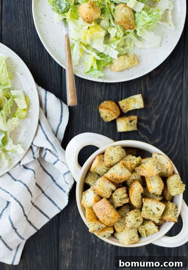 Effortless Homemade Caesar Croutons 4 An overhead shot showcasing a bounty of golden-brown Caesar croutons artfully scattered across a dark wooden background, emphasizing their texture and inviting appeal.