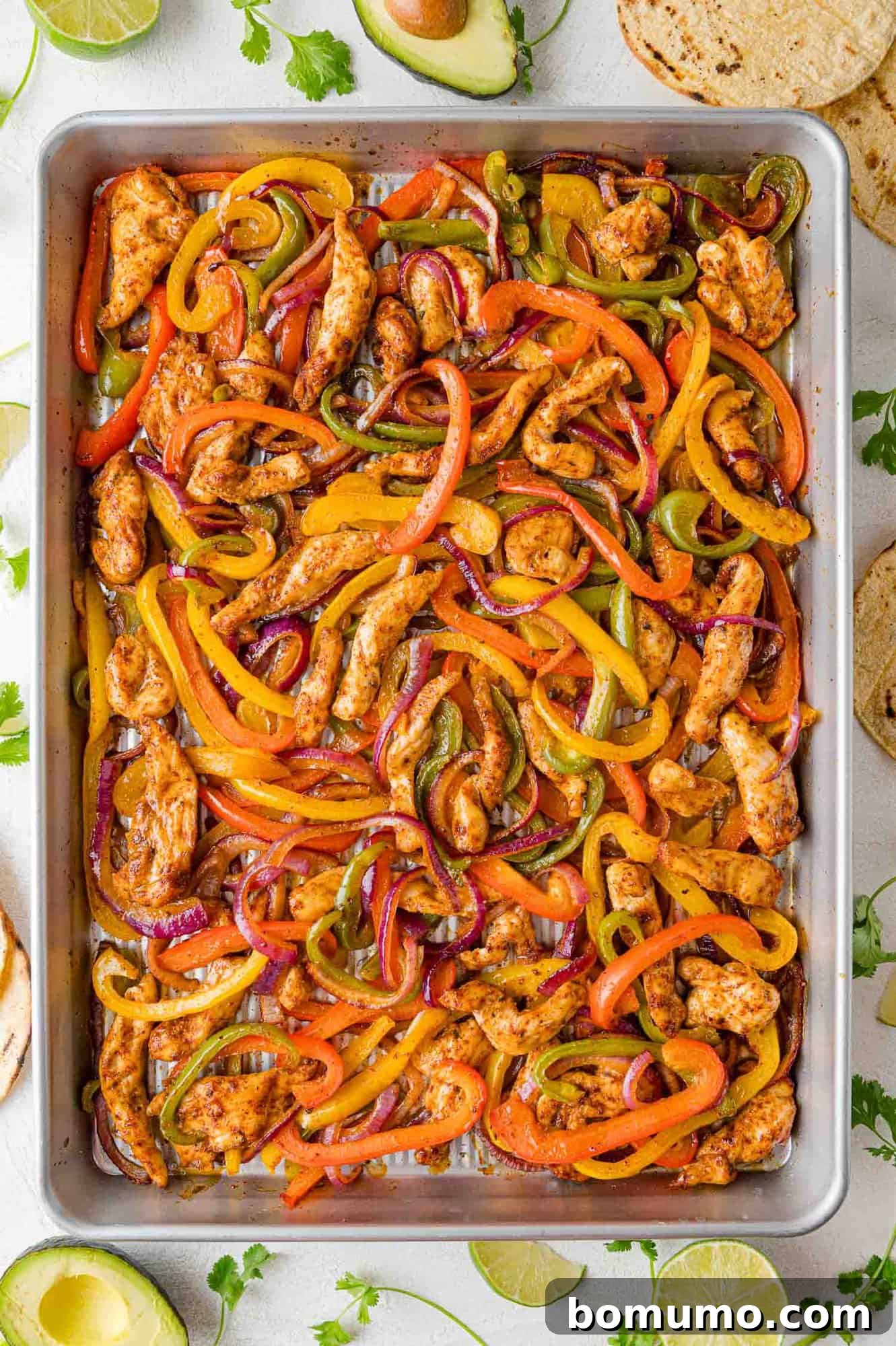 Overhead view of vibrant sheet pan chicken fajitas, bursting with colorful peppers and onions.