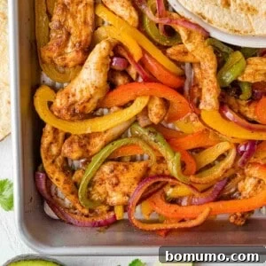 Overhead view of sheet pan fajitas with chicken, peppers, and onions, ready to be served.