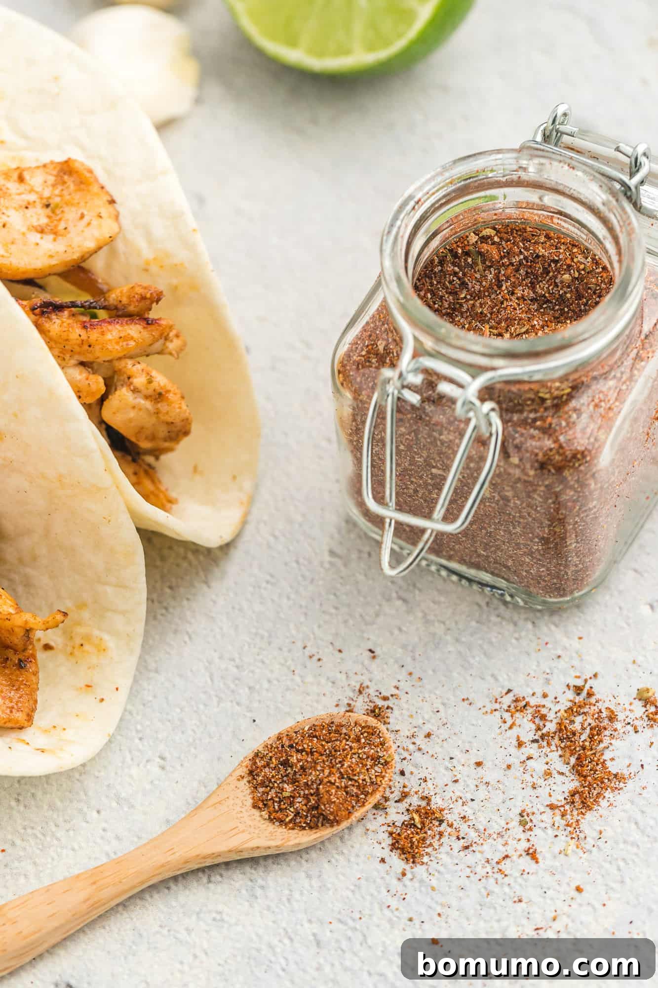 Fajitas in flour tortillas, with a jar of homemade fajita seasoning beside them.