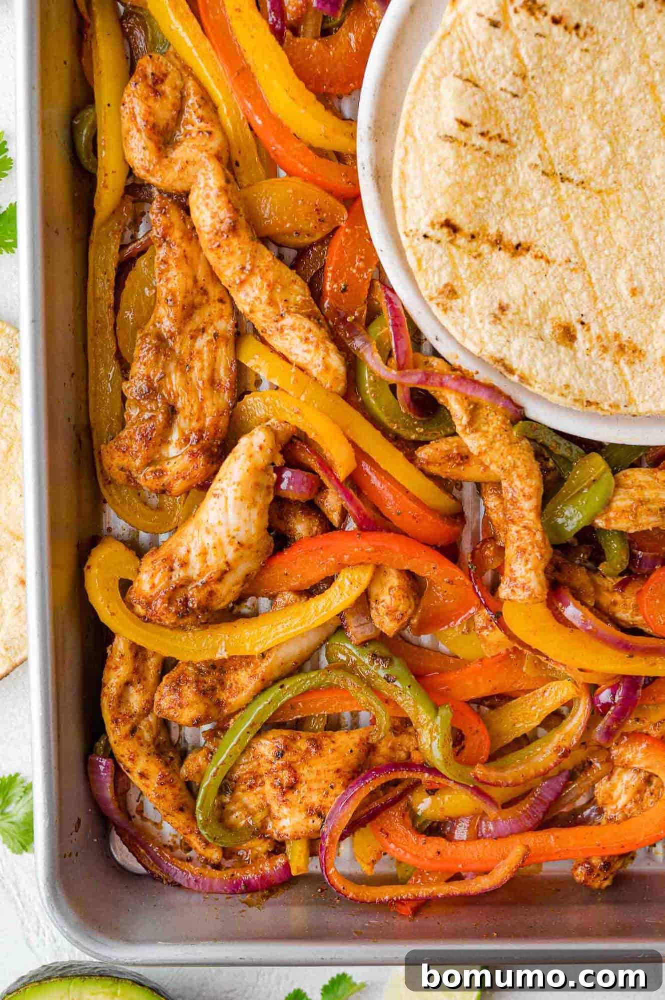 Warm tortillas artfully arranged on the pan alongside the freshly cooked chicken fajitas, ready for serving.