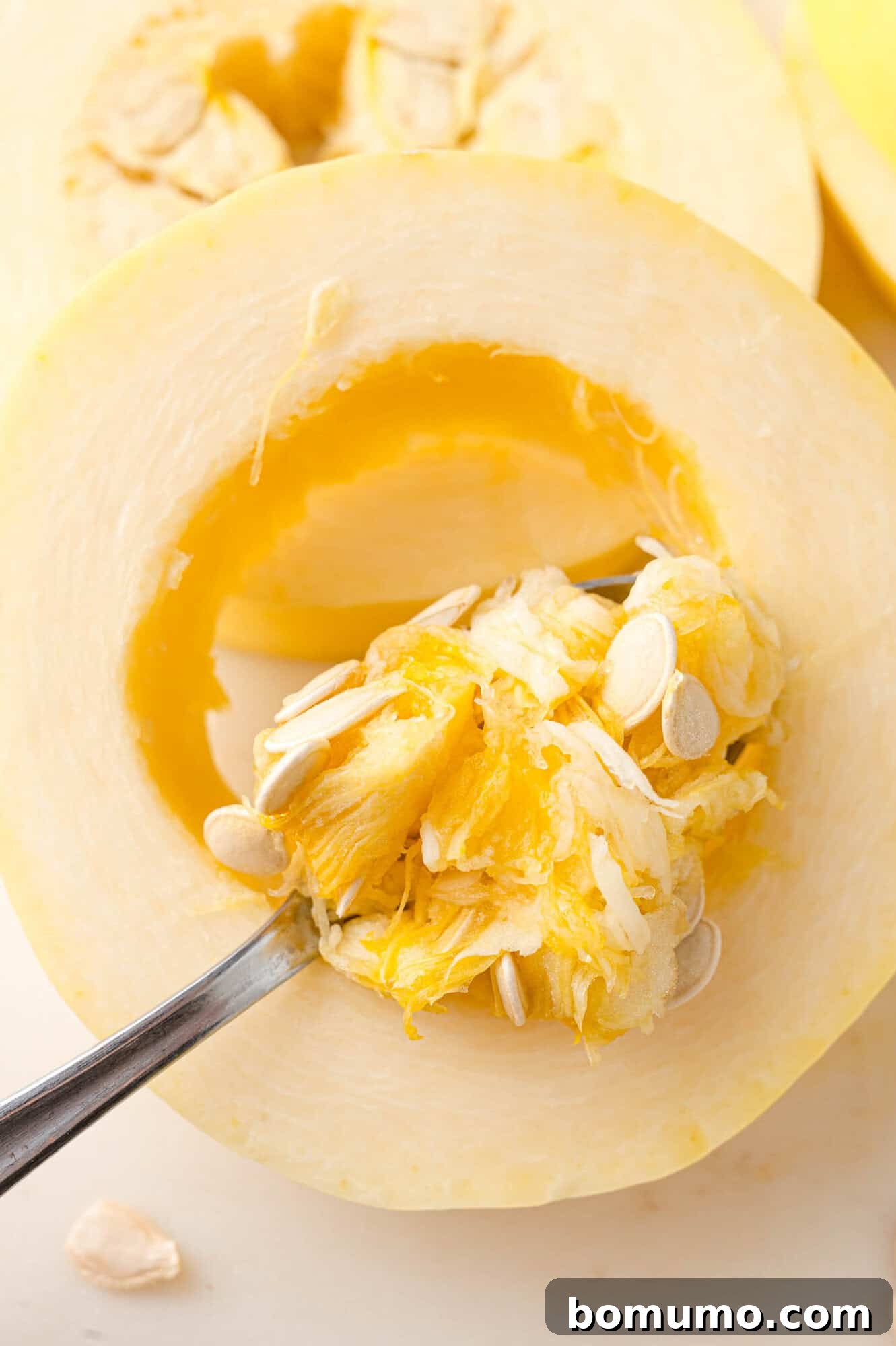 Spaghetti Squash Cooking Made Easy 4 Seeds being removed from spaghetti squash ring with a spoon.