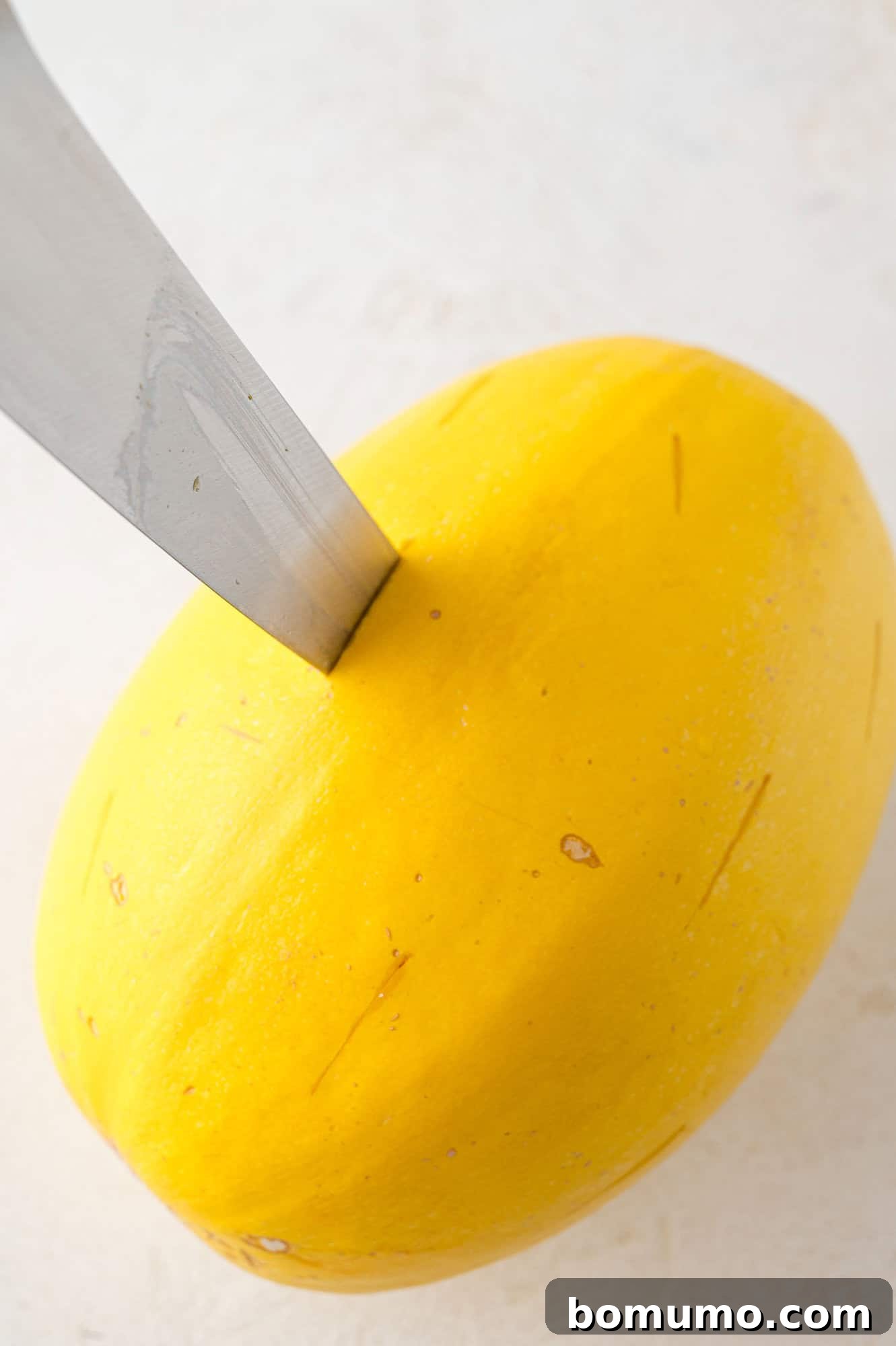 Spaghetti Squash Cooking Made Easy 7 Hole being made in a spaghetti squash with a sharp knife.