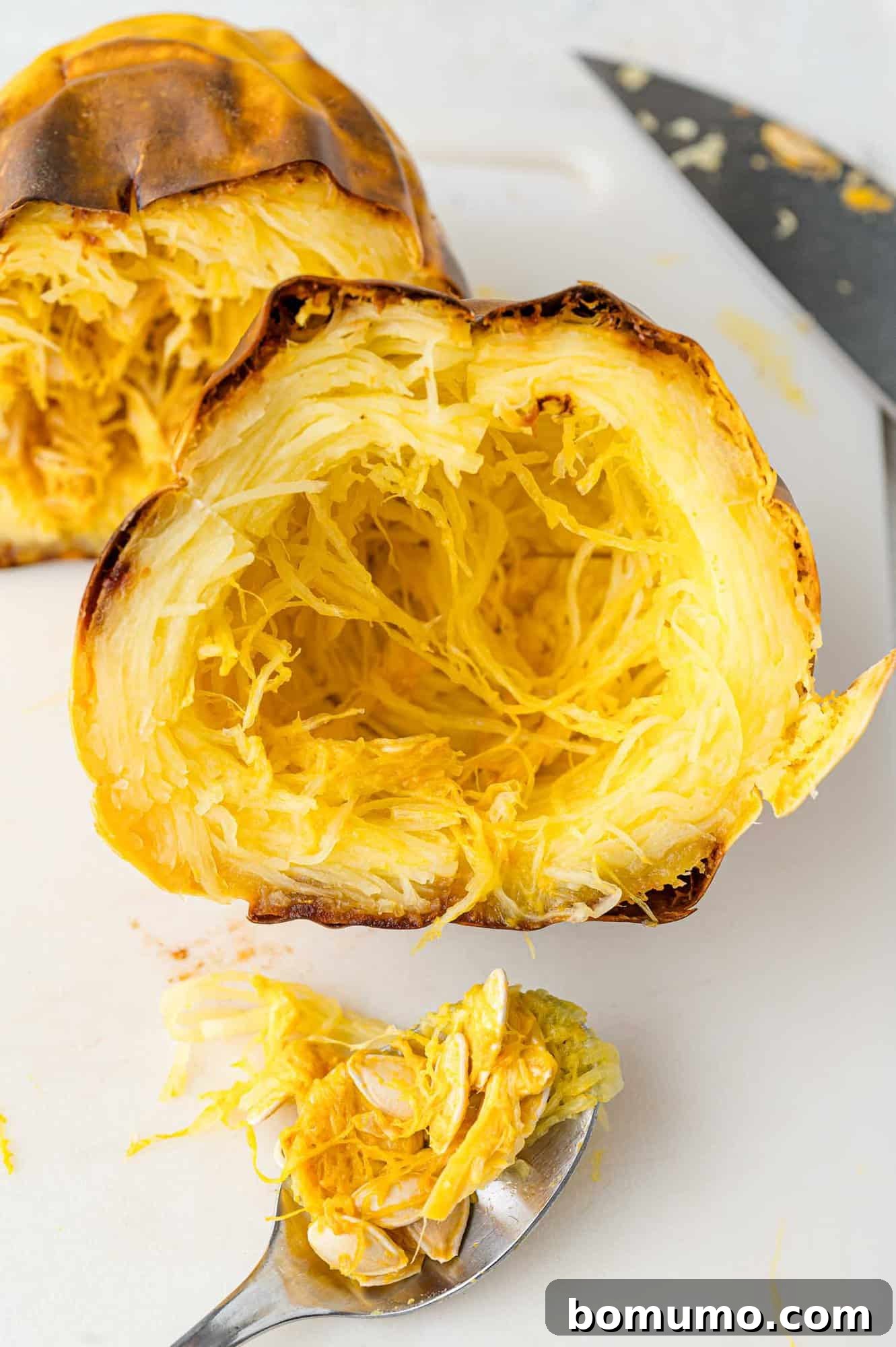 Spaghetti Squash Cooking Made Easy 9 Seeds being scooped out of baked squash half.