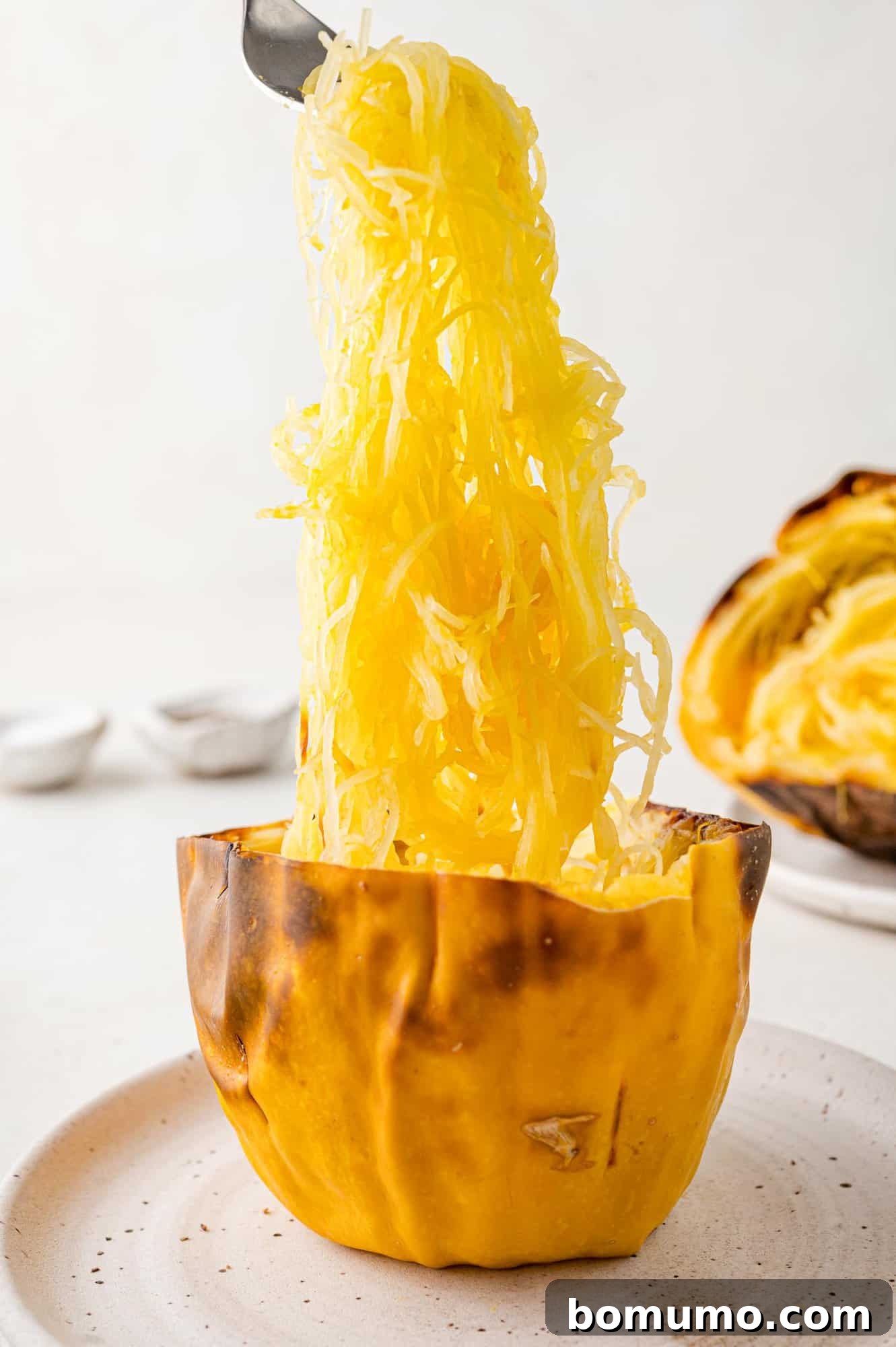 Spaghetti Squash Cooking Made Easy 10 Squash strands being lifted out of spaghetti squash half.