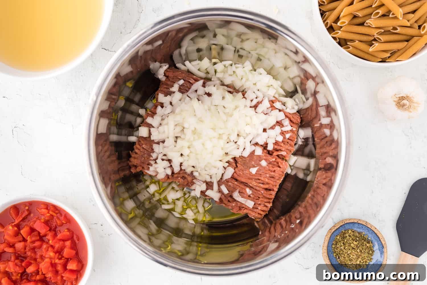 Raw Italian sausage and diced onions ready to be sautéed in the Instant Pot, showing the initial stage of cooking.