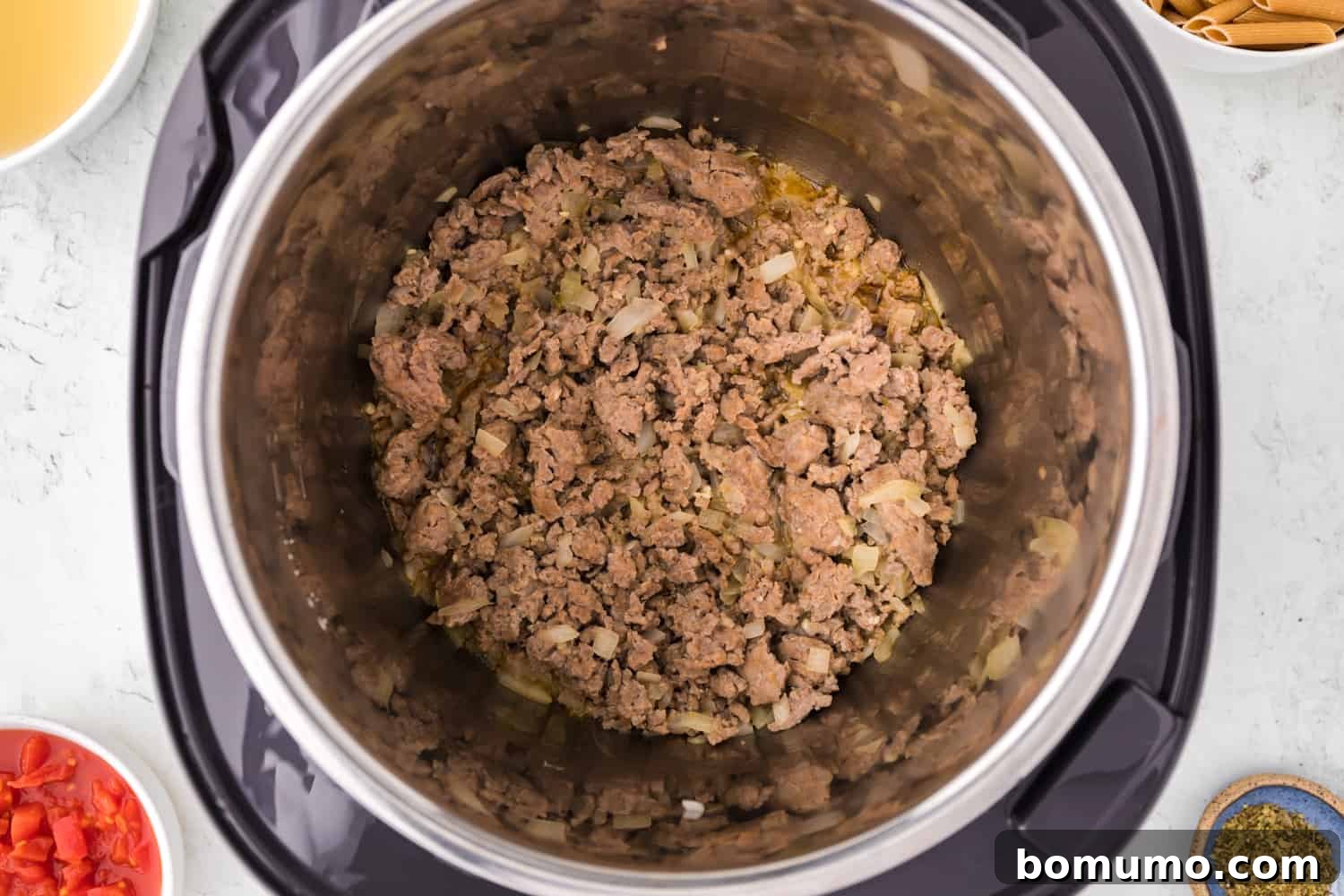 Perfectly browned sausage and translucent onions simmering in the Instant Pot, showing the progress of the first cooking stage.