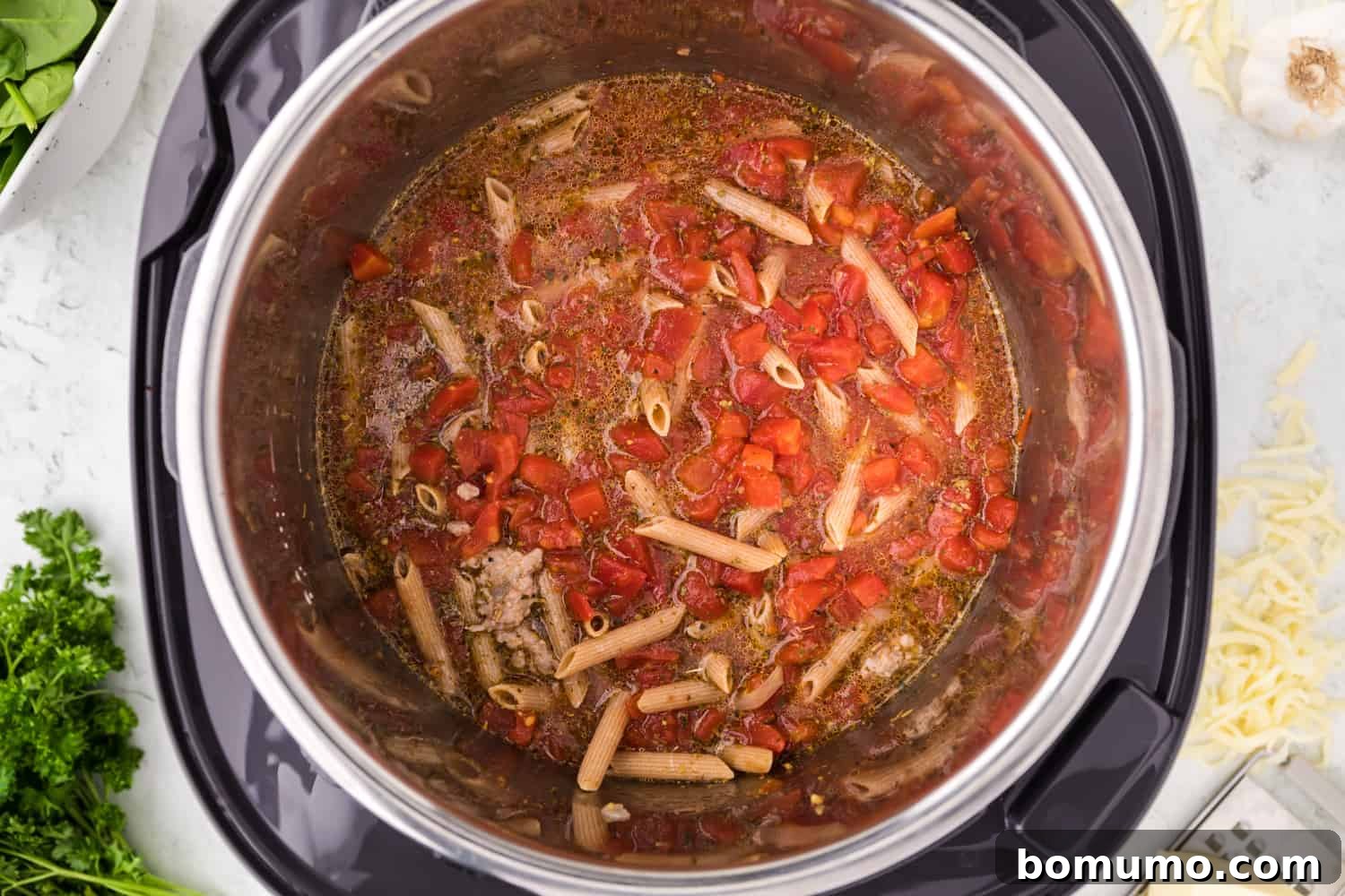 All uncooked ingredients, including pasta, diced tomatoes, and broth, combined in the Instant Pot, ready for pressure cooking.