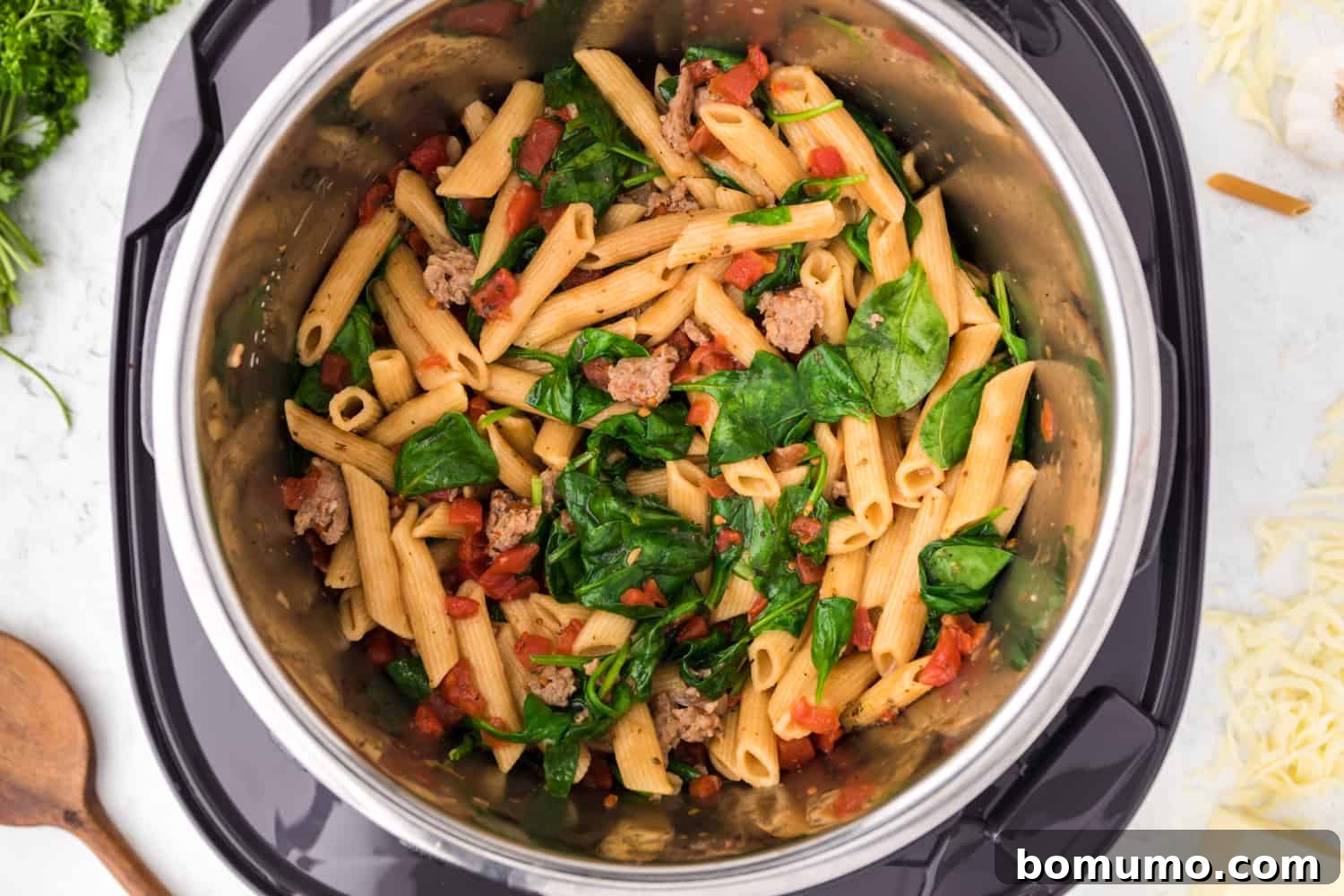 Wilted spinach fully stirred into the Instant Pot pasta, adding a vibrant green to the creamy dish.