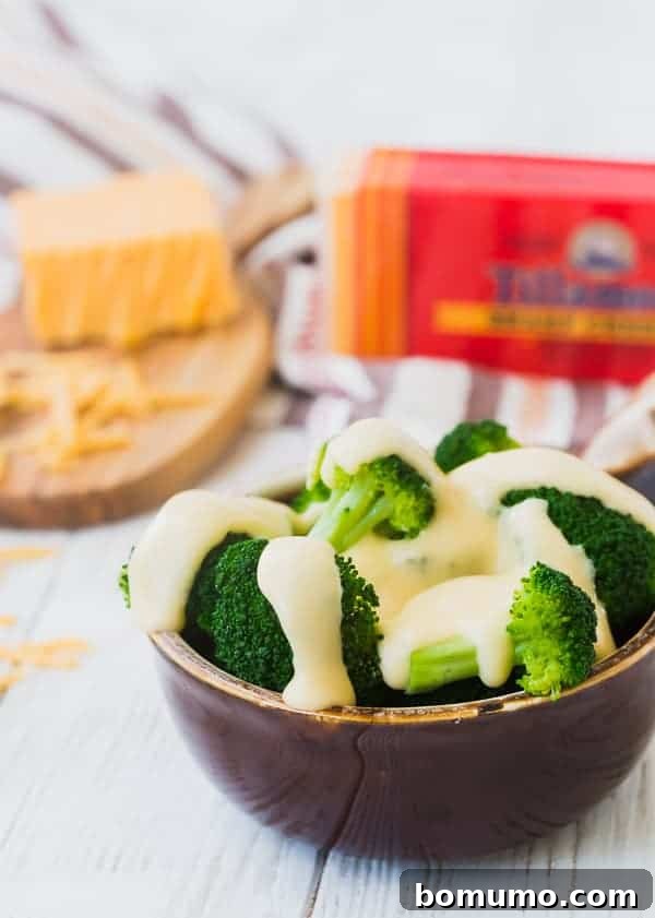 A bowl of steamed broccoli perfectly coated in luscious homemade cheese sauce.