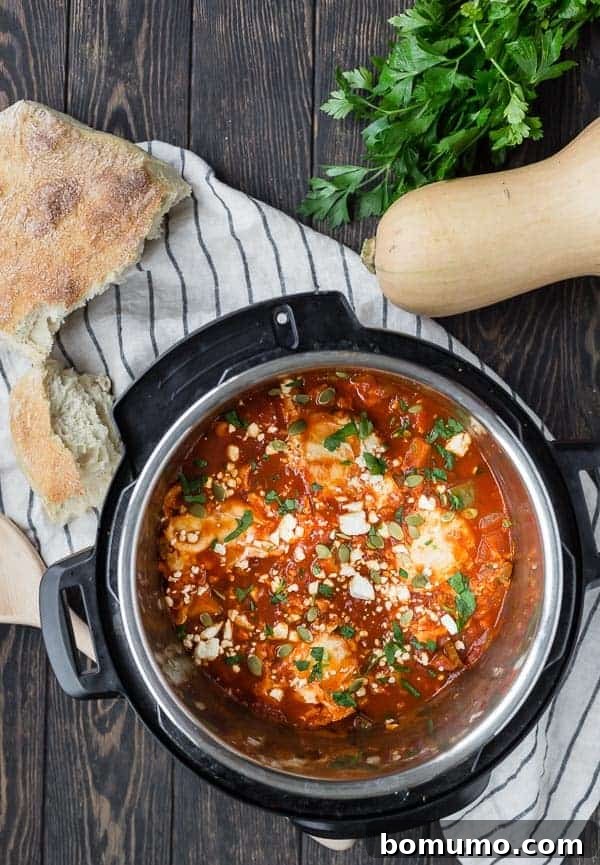 Overhead view of an Instant Pot pressure cooker filled with tomatoes, squash and eggs. Also pictured on a wooden background are a loaf of bread, a whole butternut squash, and fresh parsley.