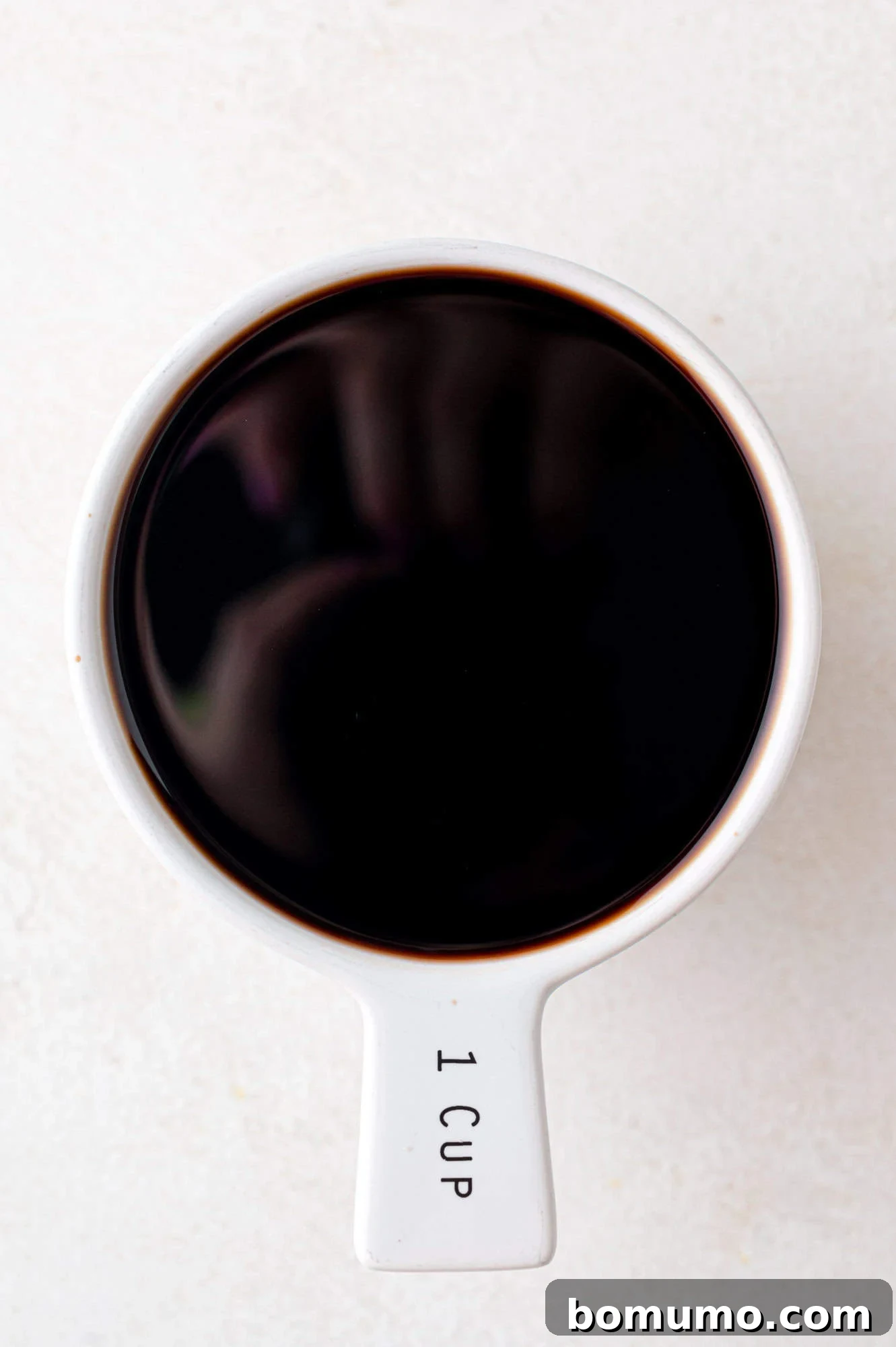 Balsamic vinegar meticulously measured into a 1 cup measuring cup, ready for reduction.
