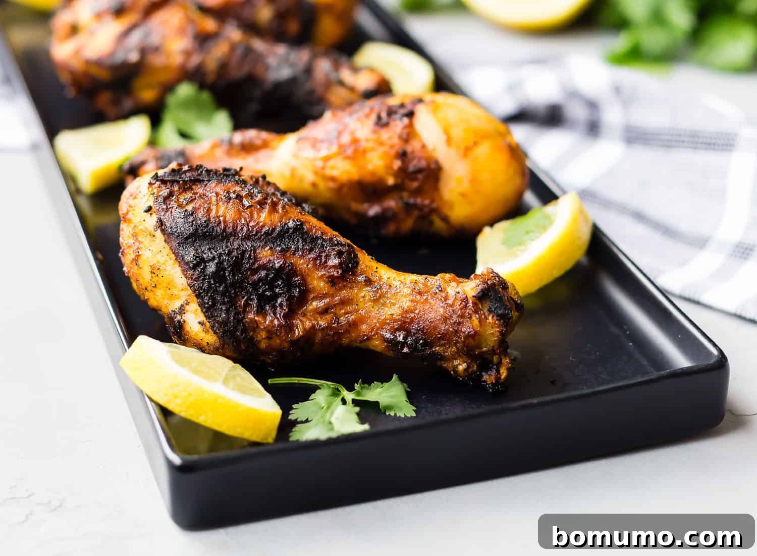 Grilled chicken drumsticks garnished with lemon and cilantro.