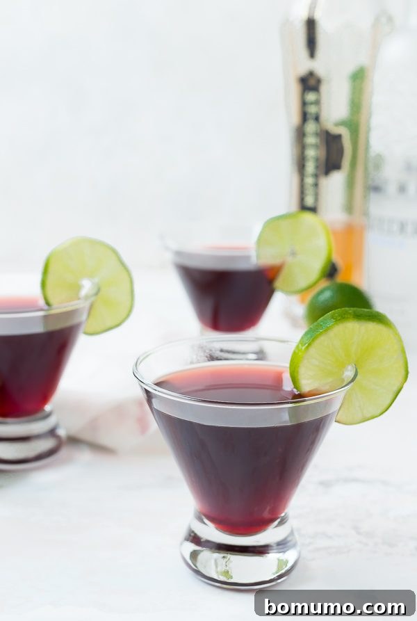 Crimson Bloom Martini 2 Front view of short martini glasses containing cherry martini, garnished with lime slice. This fruity and flavorful cocktail is easy to make.
