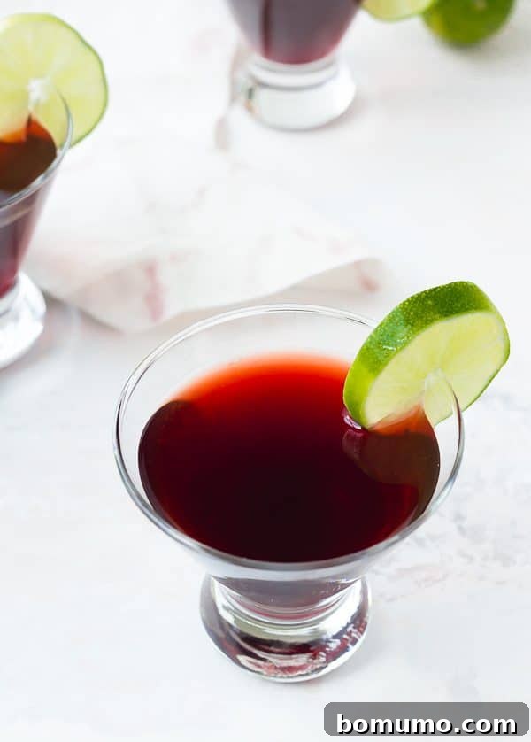 Crimson Bloom Martini 3 Overhead view of a cherry martini with lime slice garnish, on a pristine white background. A perfect blend of sweet and tart.