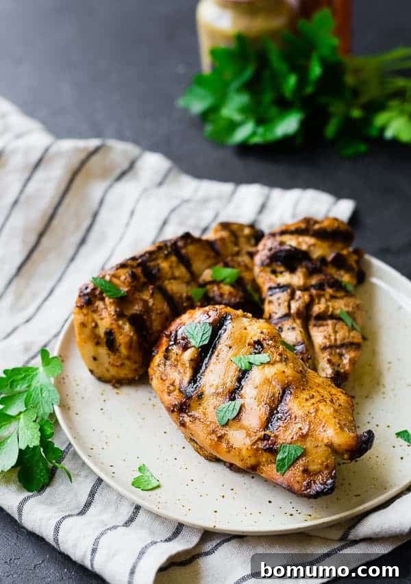 Overhead shot of three portions of perfectly grilled honey mustard chicken on a plate, ready for serving.