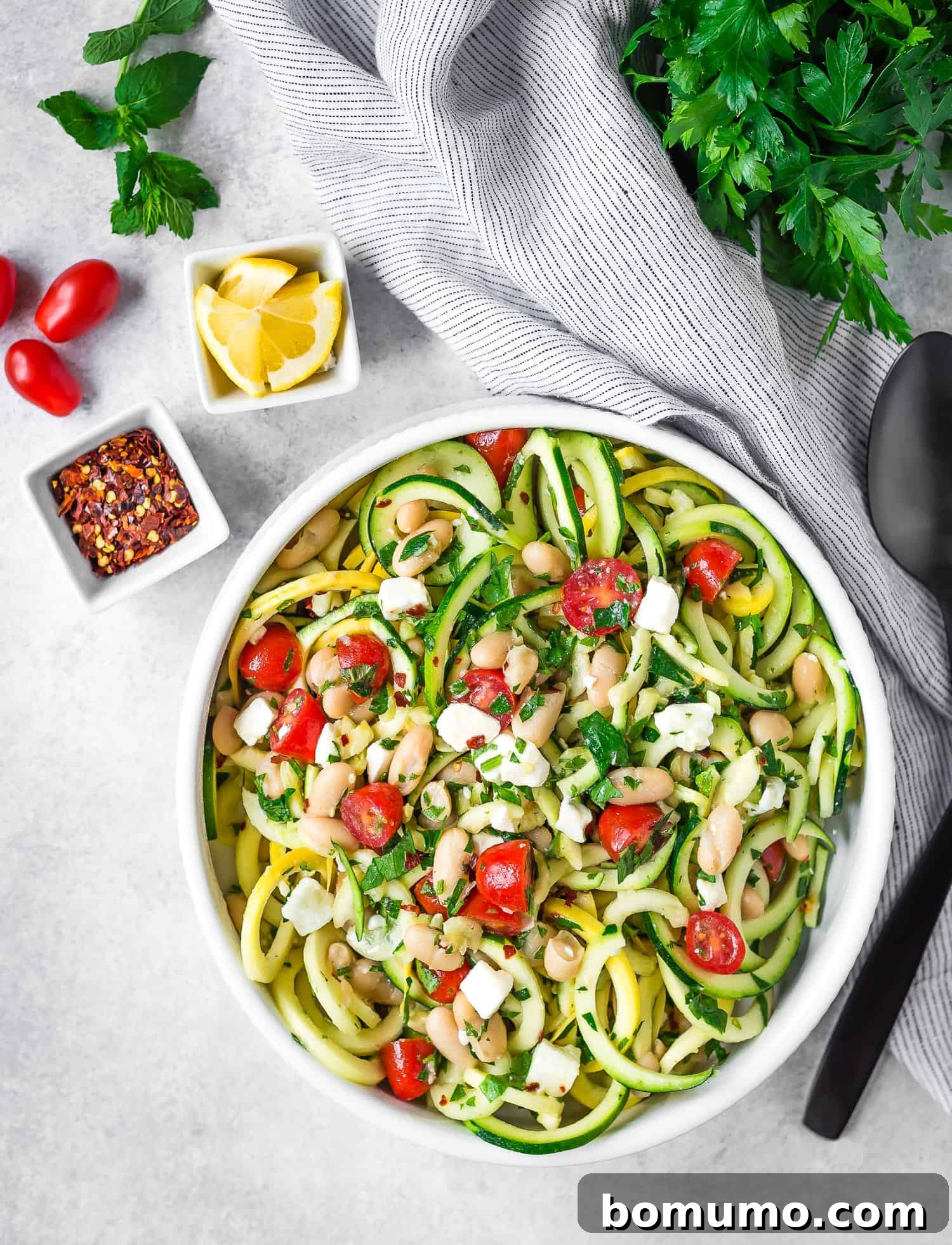 Overhead view of the vibrant zucchini noodle salad served in a elegant white serving bowl, ready to be enjoyed.