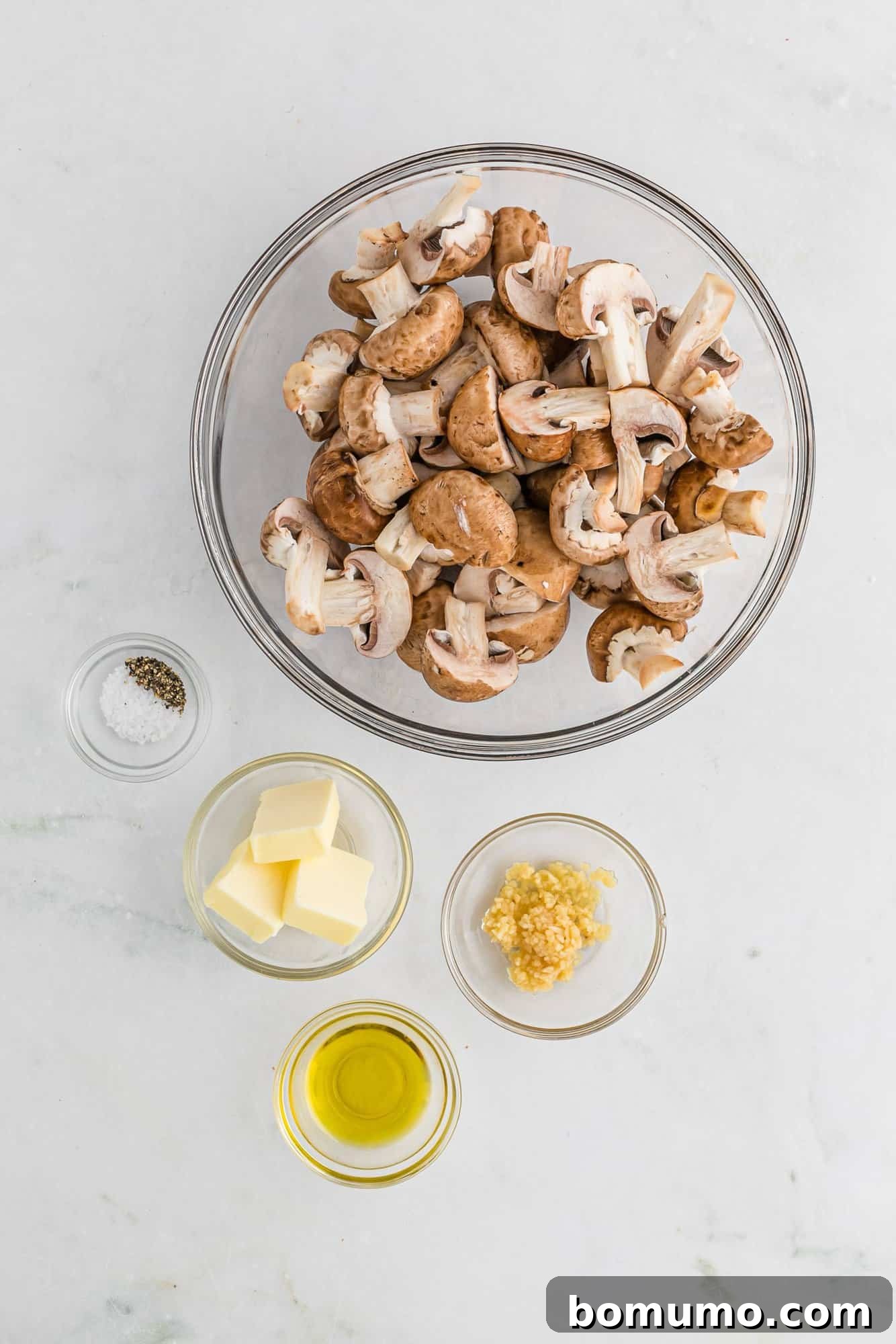 A collection of ingredients for sautéed mushrooms, including whole mushrooms, garlic cloves, and fresh parsley.