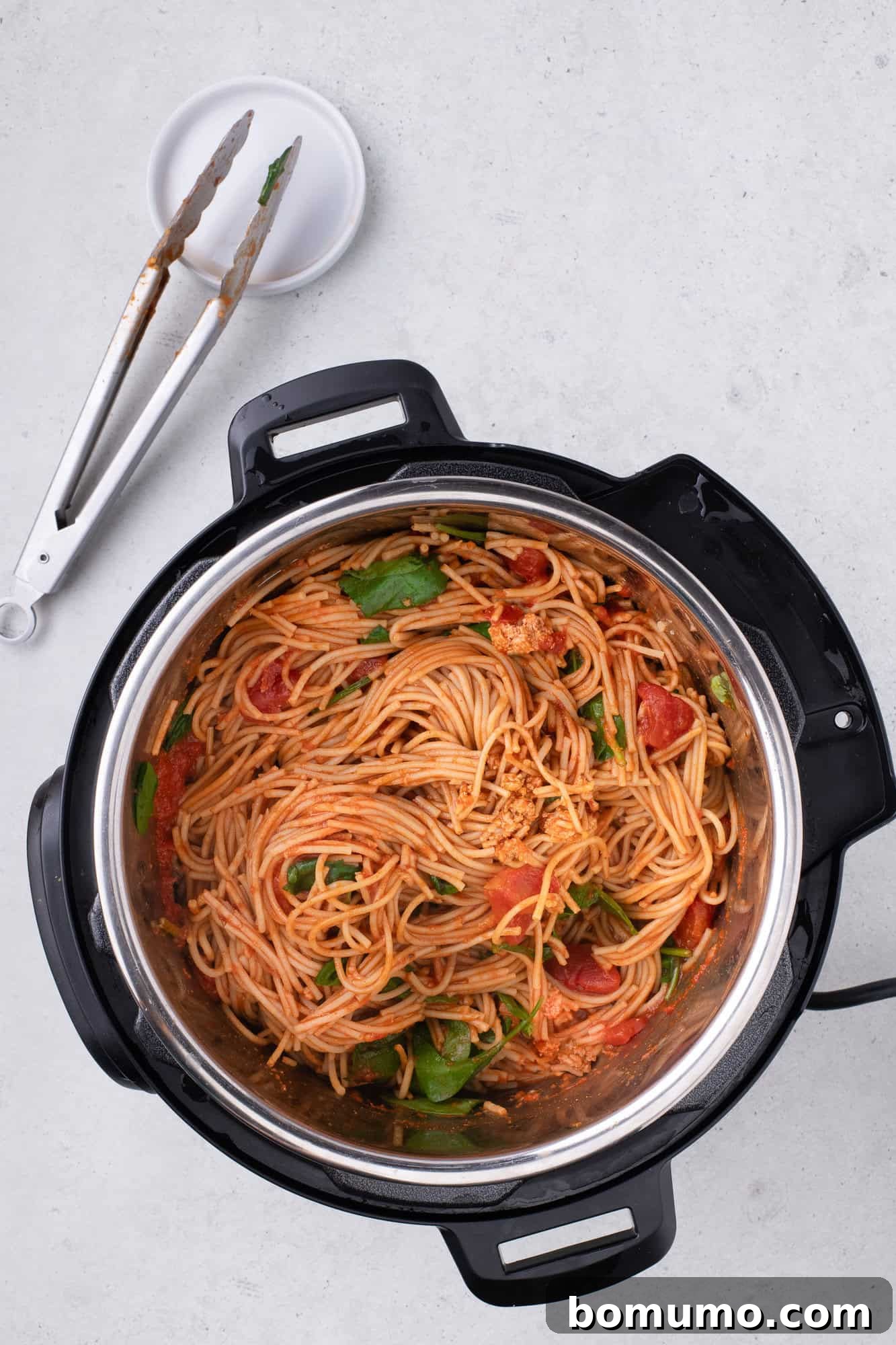 Completed Instant Pot Spaghetti with vibrant, wilted spinach, perfectly mixed and ready to be served directly from the pressure cooker, showcasing a delicious one-pot meal.