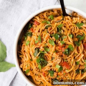 Overhead view of spaghetti and meat sauce in a white bowl, sprinkled with fresh parsley.