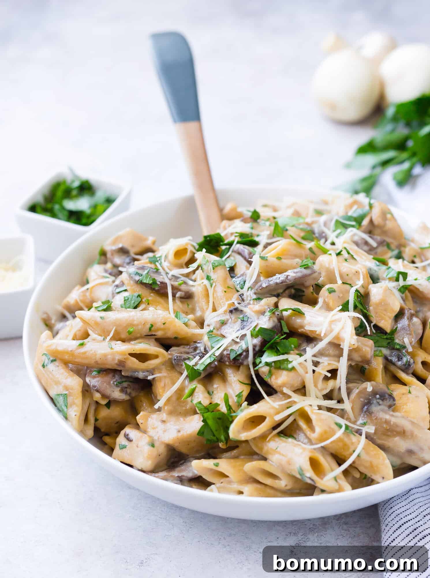 Chicken marsala pasta with a wooden spoon.