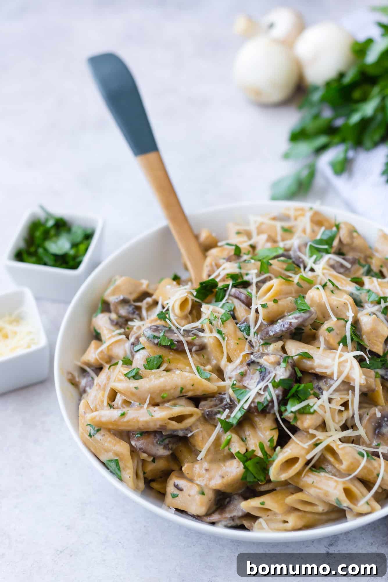 Pasta with chicken and mushrooms in a large white serving bowl.