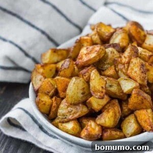 Small oval shaped white bowl filled to the brim with roasted potato pieces.