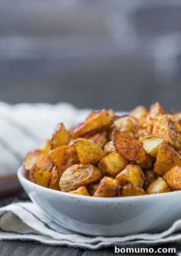Close up view of roasted potatoes that are golden brown in color, placed in a small white bowl.